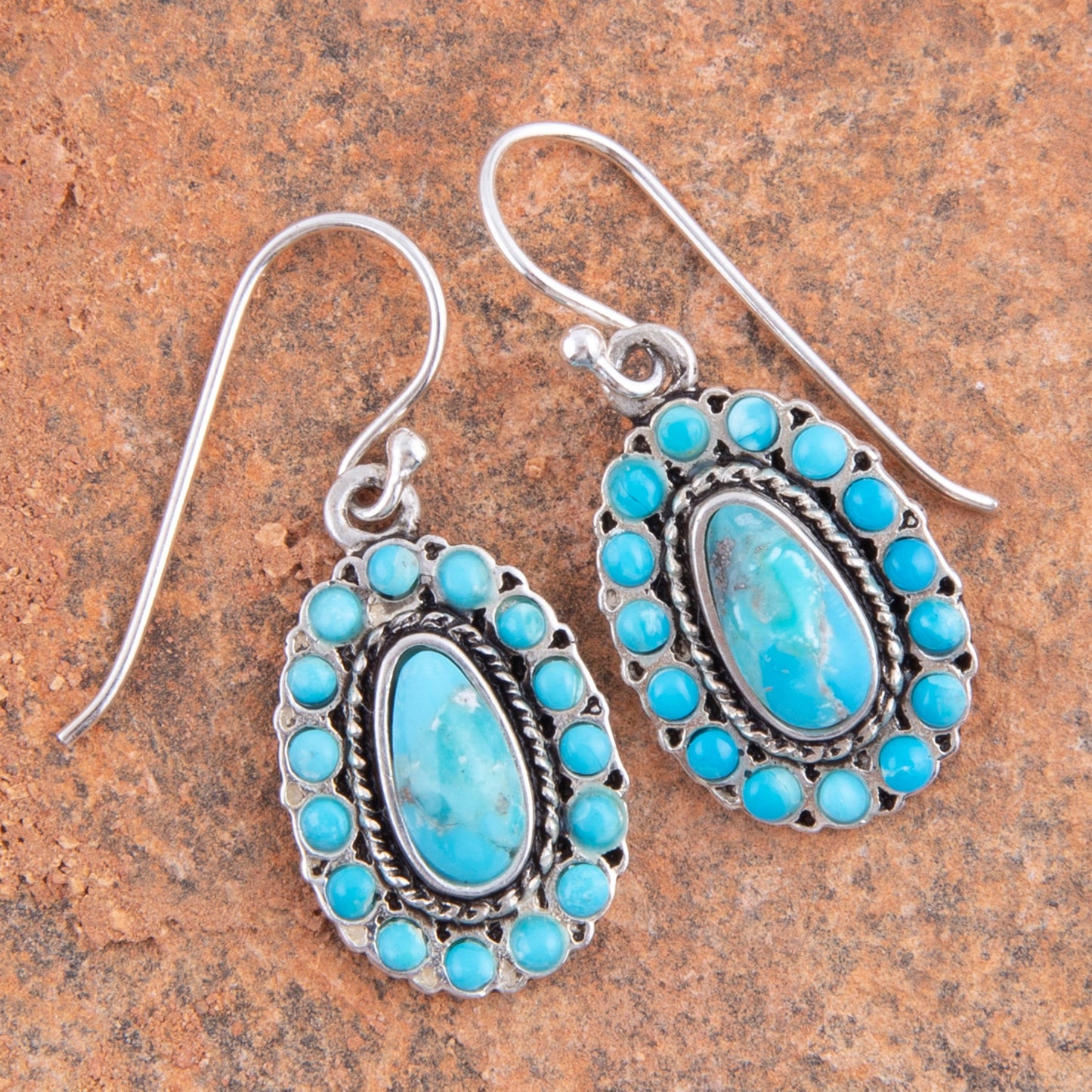 Pair of silver earrings with blue stones on a brown stone background