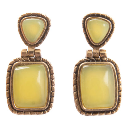 Pair of earrings with yellow gemstones and bronze frames on a white background
