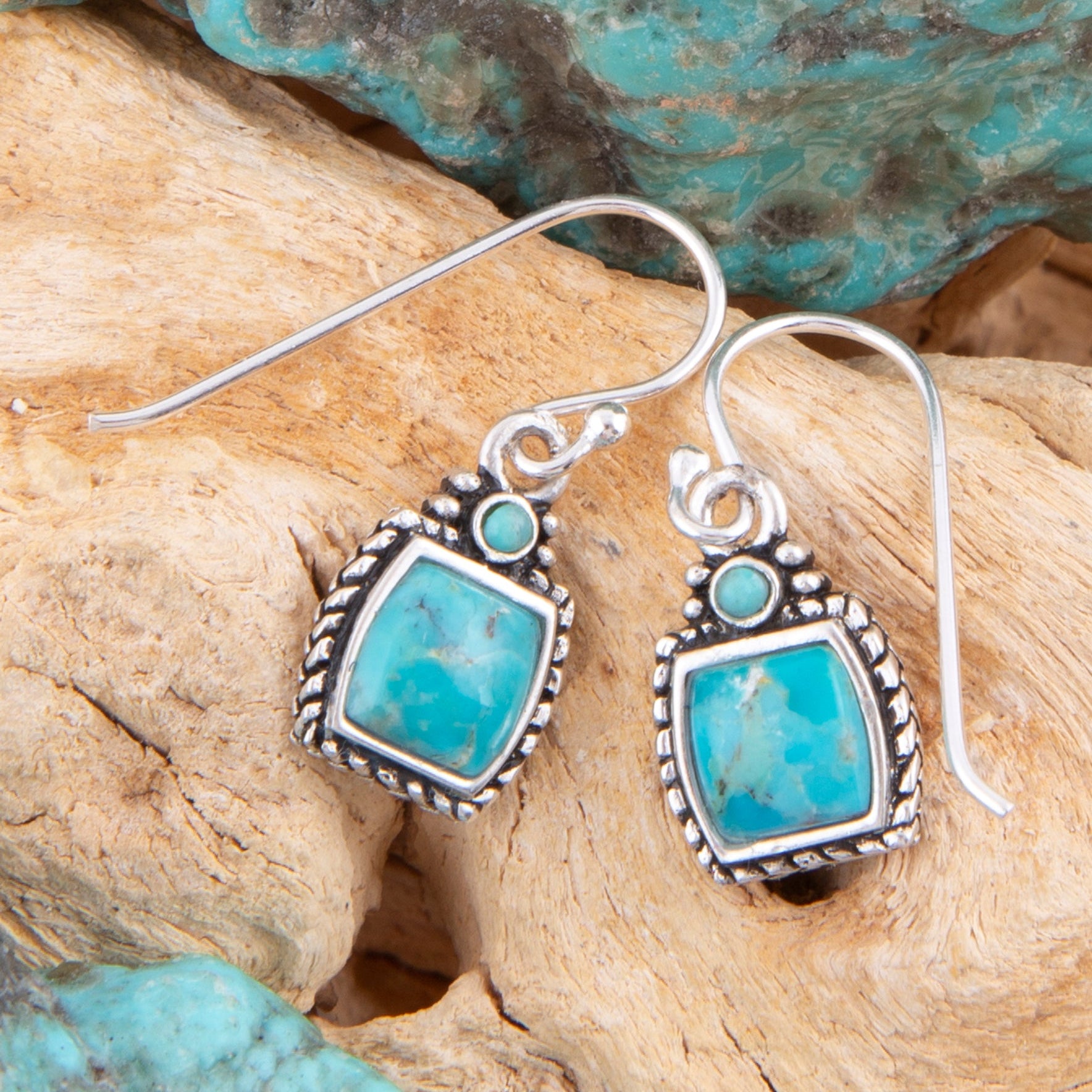 Turquoise earrings with silver hooks on a natural stone background