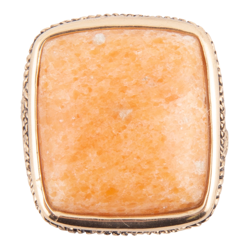 A square gold ring featuring a textured, peach-orange stone cabochon, shown against a plain white background.