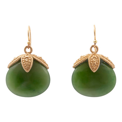 A pair of gold and green drop earrings on a plain white background. Each earring features a smooth, oval-shaped green stone pendant capped with an ornate, textured gold leaf-like setting and a gold fishhook ear wire.