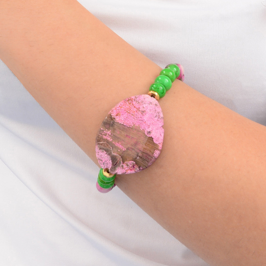 Bracelet with pink and green beads on a wrist against a white background