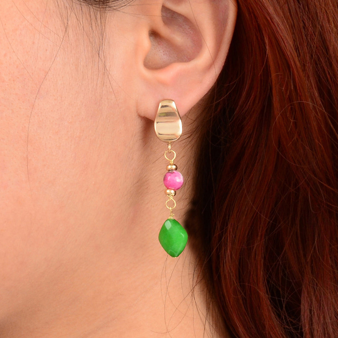 Gold earring with pink and green beads worn by a person with red hair.