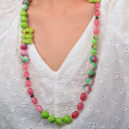 Necklace with green and pink beads worn by a person in a white blouse.