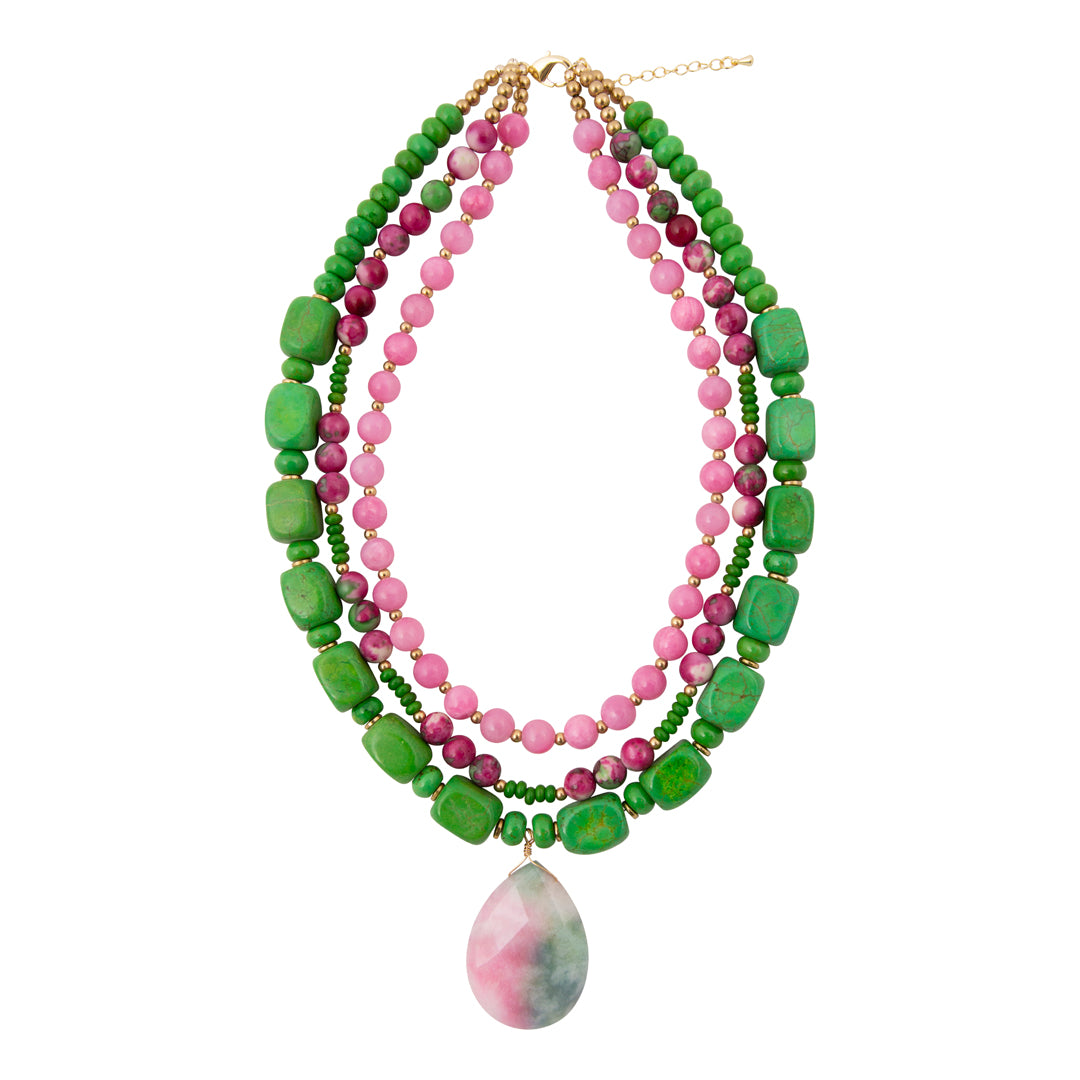 Stack of green and pink beaded necklaces with a pendant on a white background