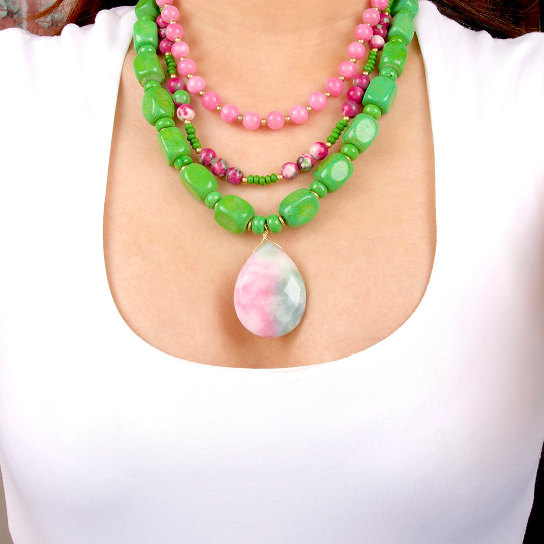 Necklace with green and pink beads and a teardrop-shaped pendant on a white background