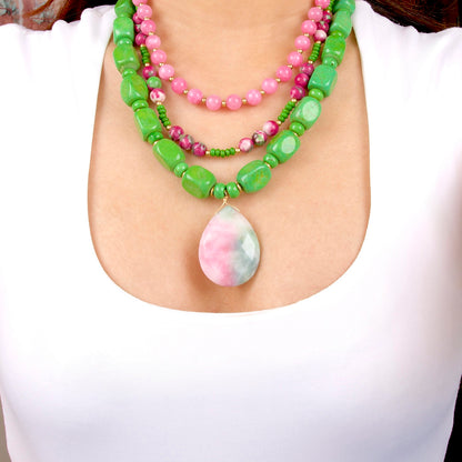 Necklace with green and pink beads and a teardrop-shaped pendant on a white background
