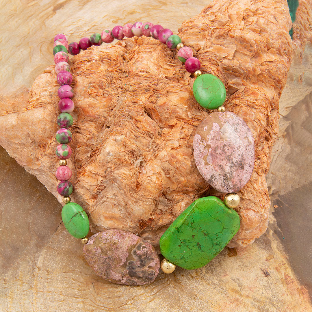 Necklace with green and pink beads on a textured stone surface
