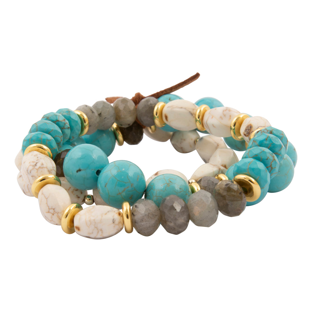 A multi-strand beaded wrap bracelet featuring turquoise, white marbled, and gray stone beads separated by gold spacer rings, with a brown leather tie closure, shown on a plain white background.