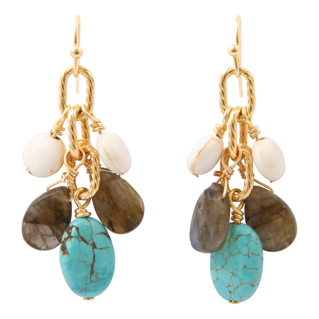A pair of gold dangle earrings featuring white beads, brown stones, and a prominent turquoise stone, shown against a plain white background.