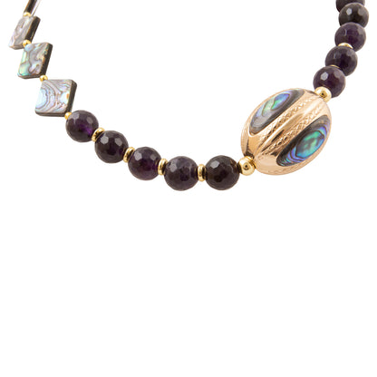 A beaded necklace featuring faceted dark purple beads, square iridescent abalone shell tiles, and a large oval gold-tone clasp with abalone shell inlays, shown on a plain white background.