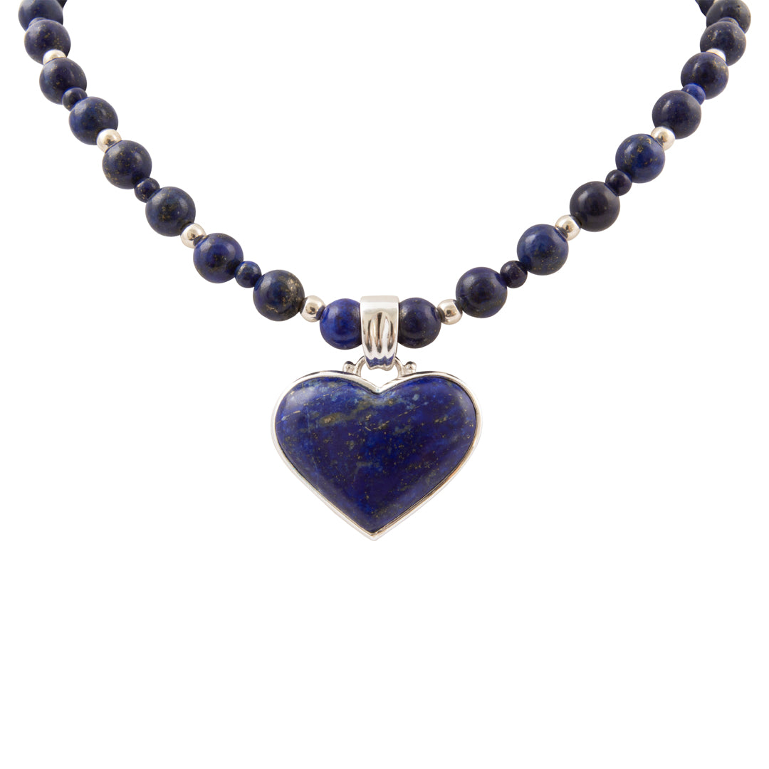 A beaded necklace featuring dark blue lapis lazuli stones and polished silver-toned spacer beads, with a heart-shaped lapis lazuli pendant in a silver bezel setting, shown against a plain white background.