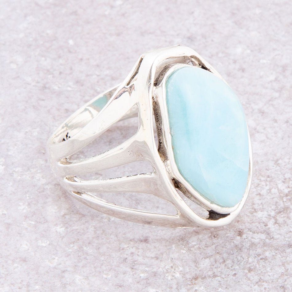Silver ring with a light blue stone on a textured beige background