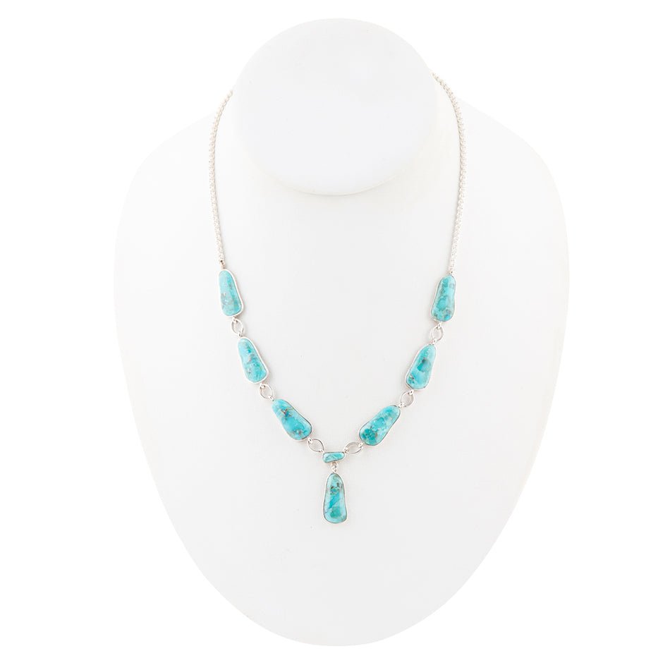 Turquoise necklace on a white stand with a white background