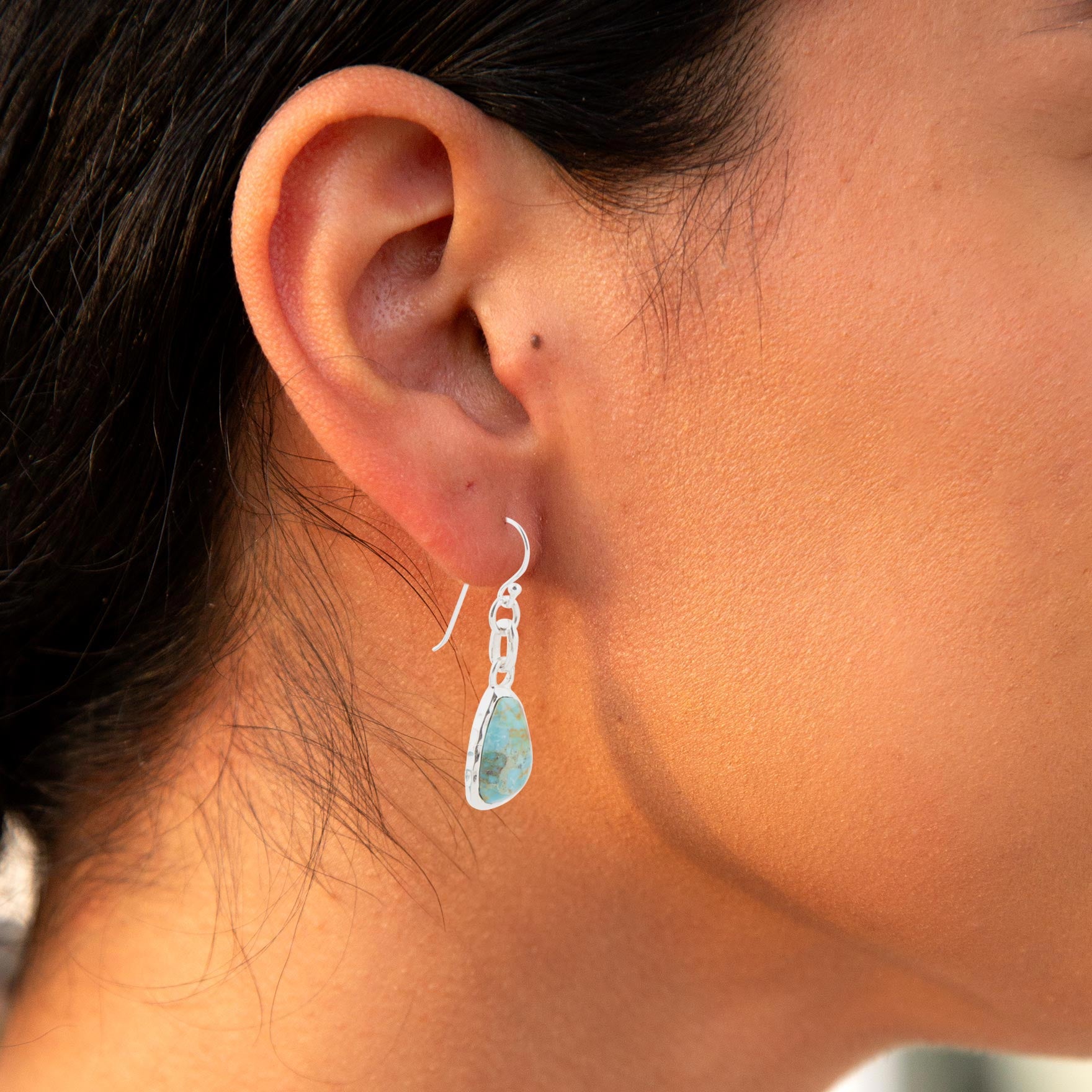Close-up of an ear wearing a unique earring with a blurred background
