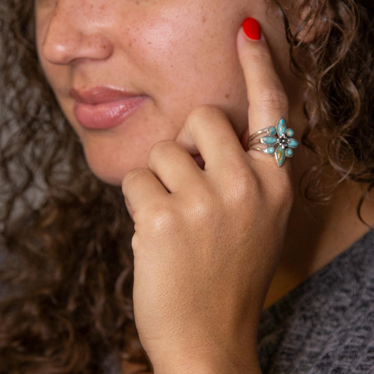 Close-up of a woman's hand with a ring, touching her face.