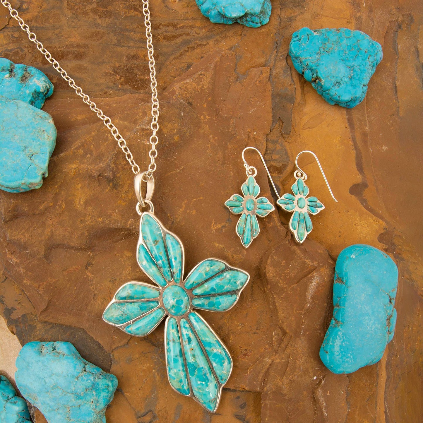Turquoise butterfly necklace and earrings on a textured brown surface with turquoise stones.