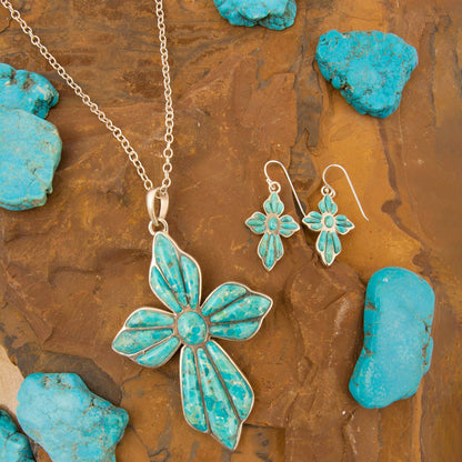Turquoise butterfly necklace and earrings on a textured brown surface with turquoise stones.
