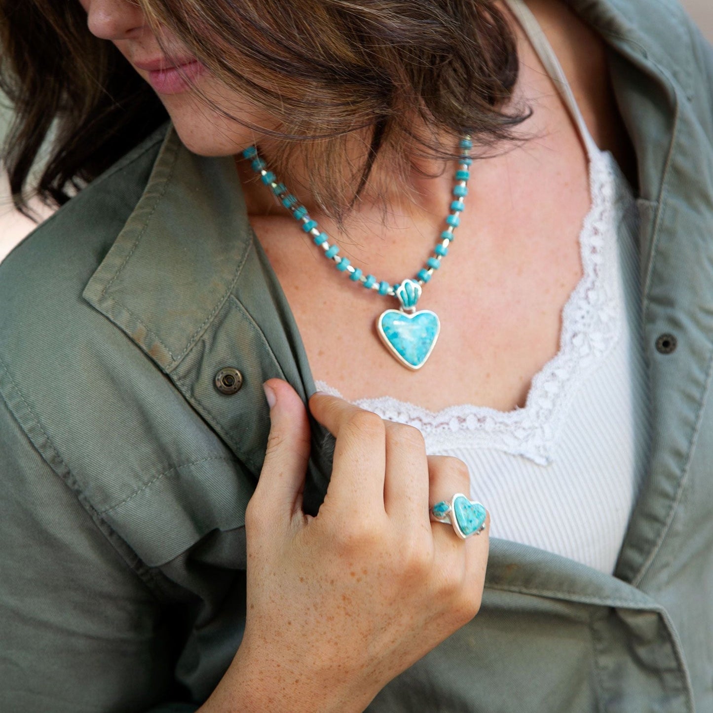 Person wearing a turquoise beaded necklace and heart-shaped pendant