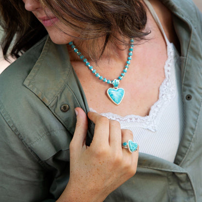 Person wearing a turquoise beaded necklace and heart-shaped pendant