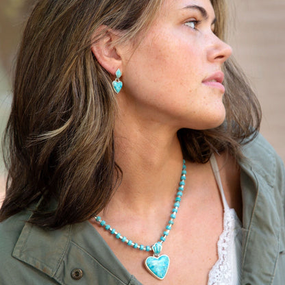 Woman wearing turquoise heart-shaped earrings and necklace