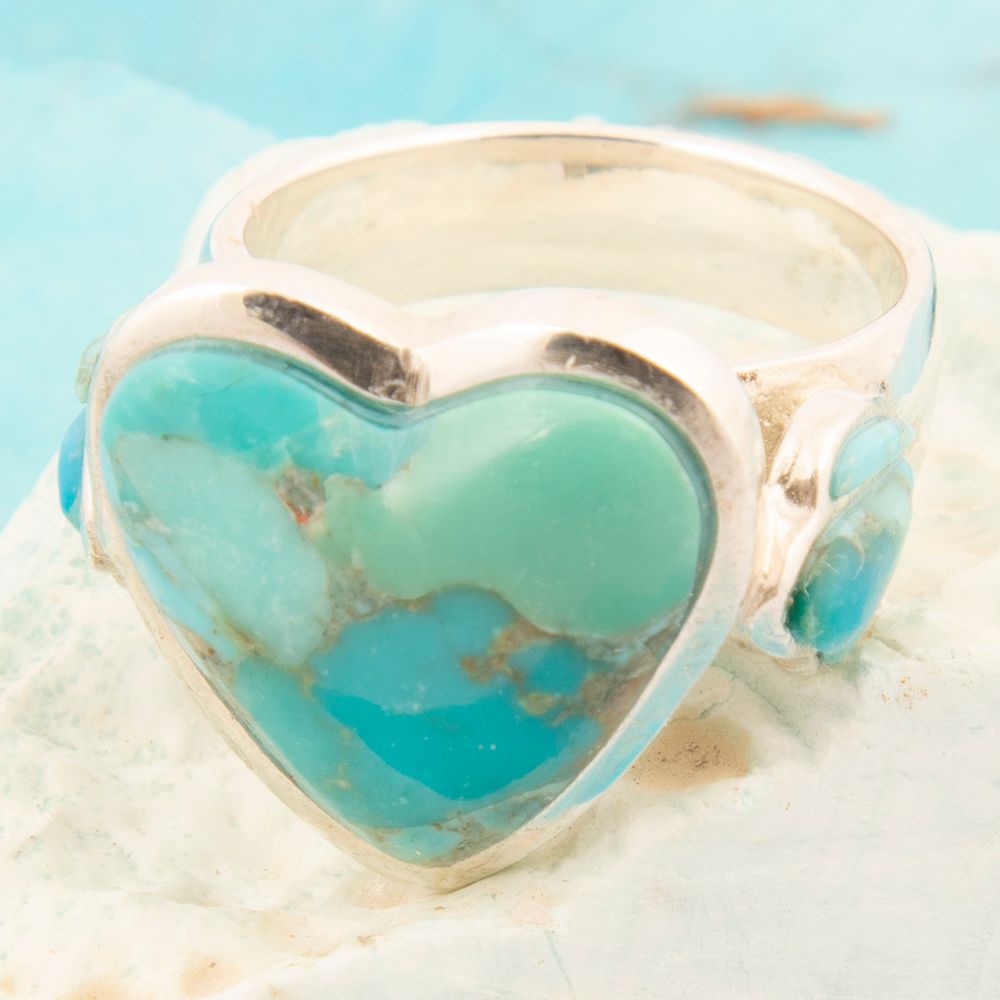 Silver ring with a heart-shaped turquoise stone on a light blue background