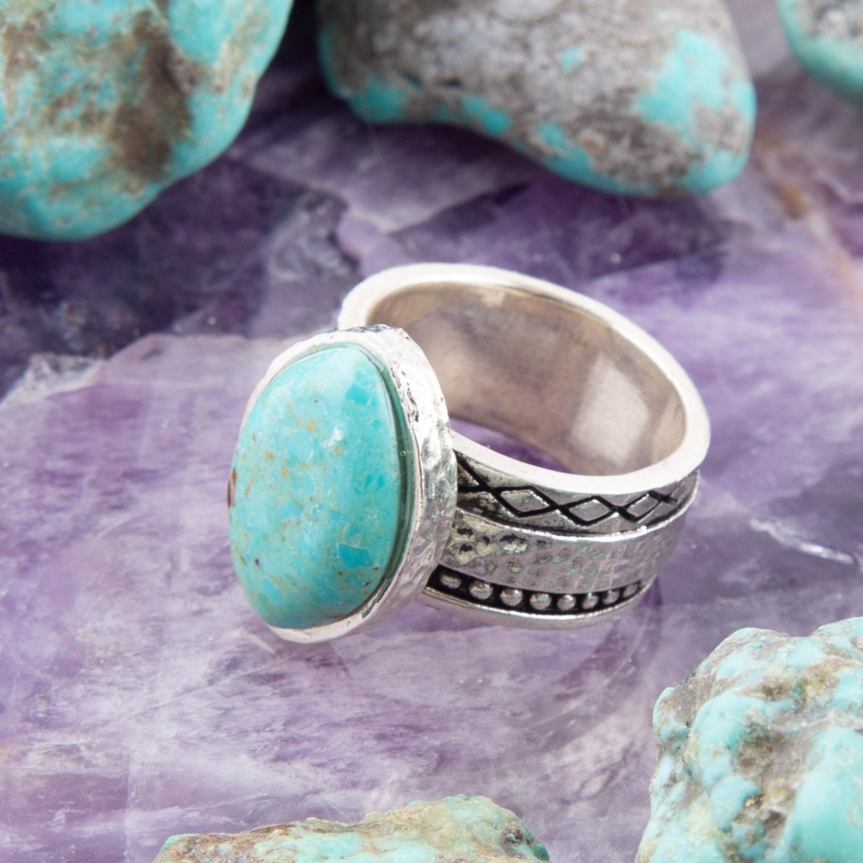 Turquoise stone ring with silver band on a purple stone background