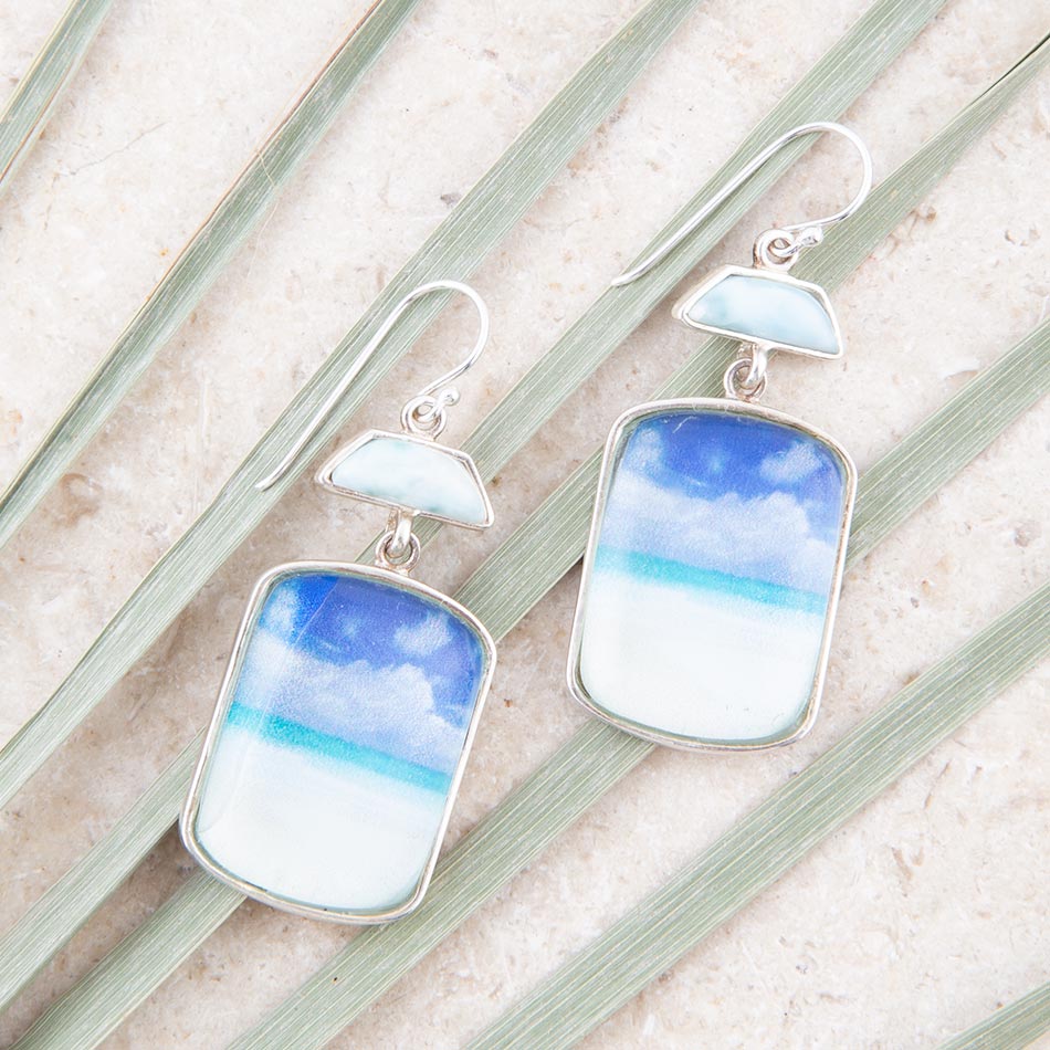 Pair of earrings with blue and white designs on a textured surface