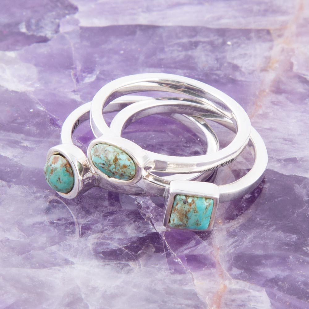 Set of silver rings with turquoise stones on a purple crystal background