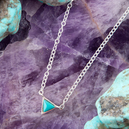 Necklace with a turquoise triangle pendant on a purple crystal background