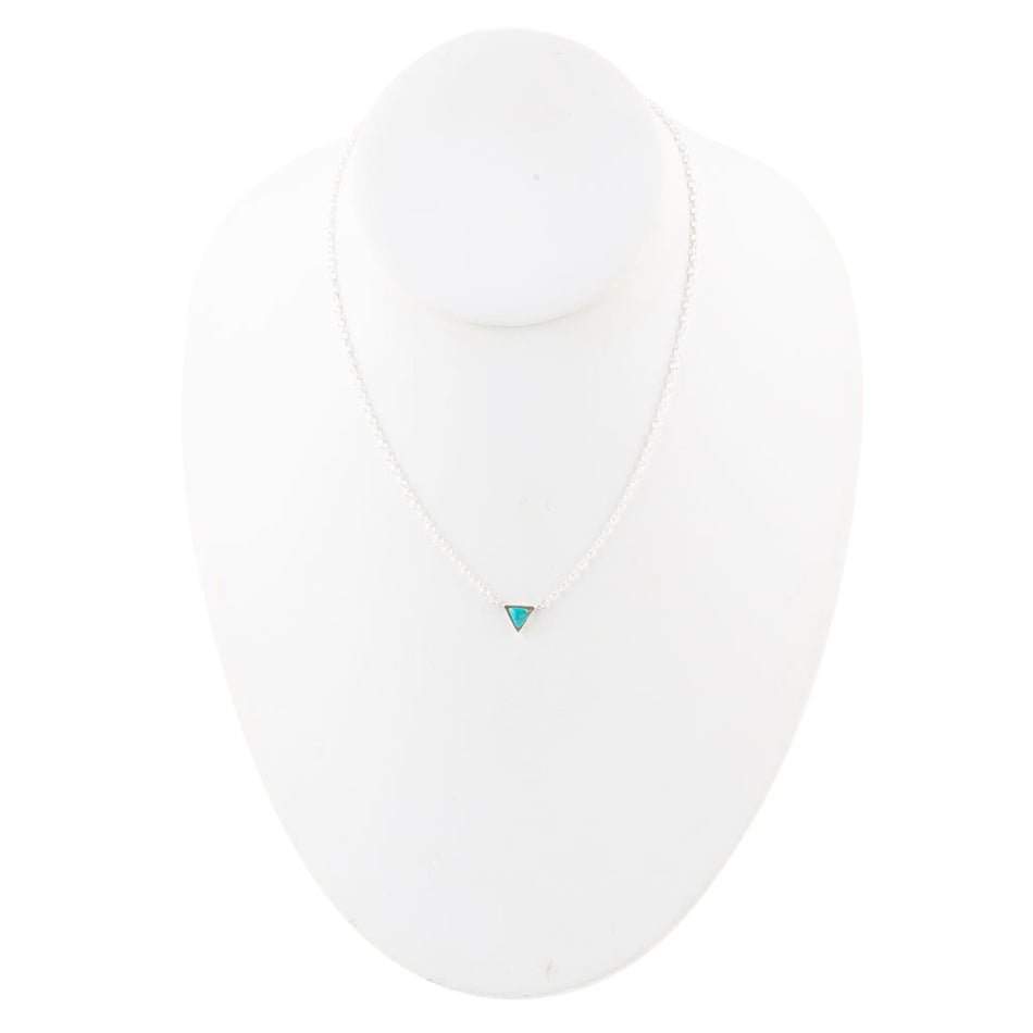 White shirt with a small turquoise heart emblem on a white background